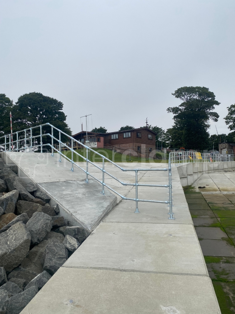 Safety barrier constructed from tube clamp fittings installed at a seafront slipway